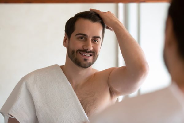 Smiling man look in mirror in bath style hair