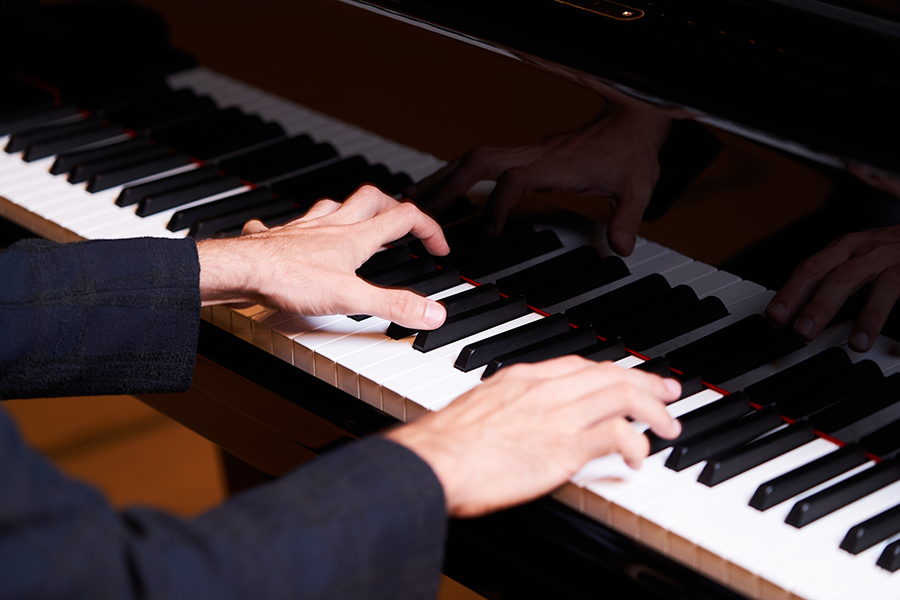 Closeup man's hand playing the grand piano keyboard