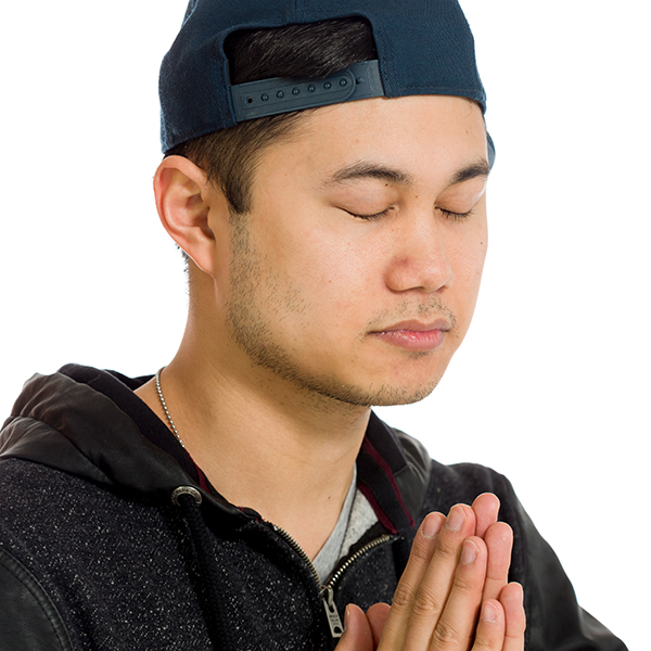 Man praying with baseball cap on