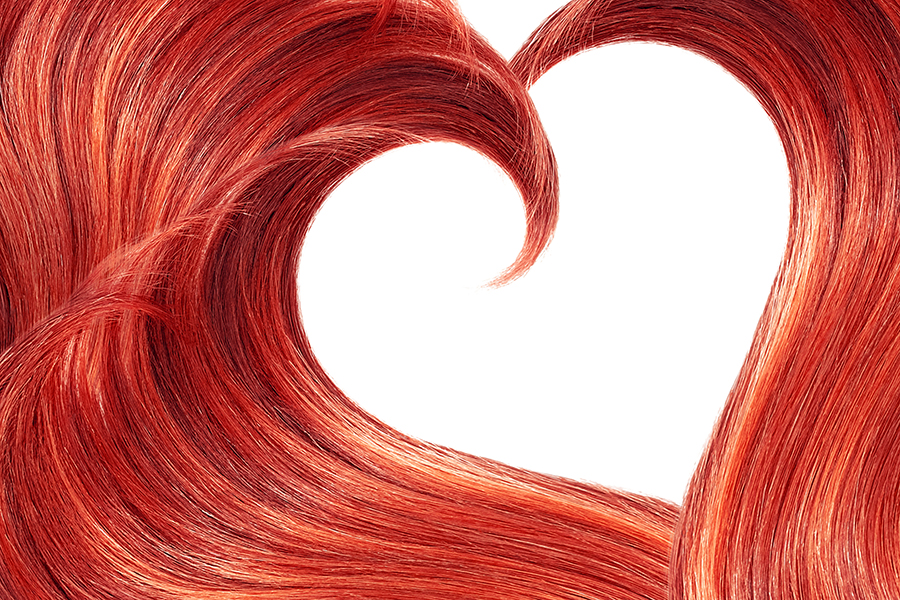 Red hair in shape of heart on white