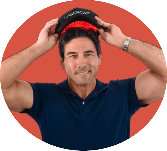 Man wearing LaserCap red light therapy cap on orange background
